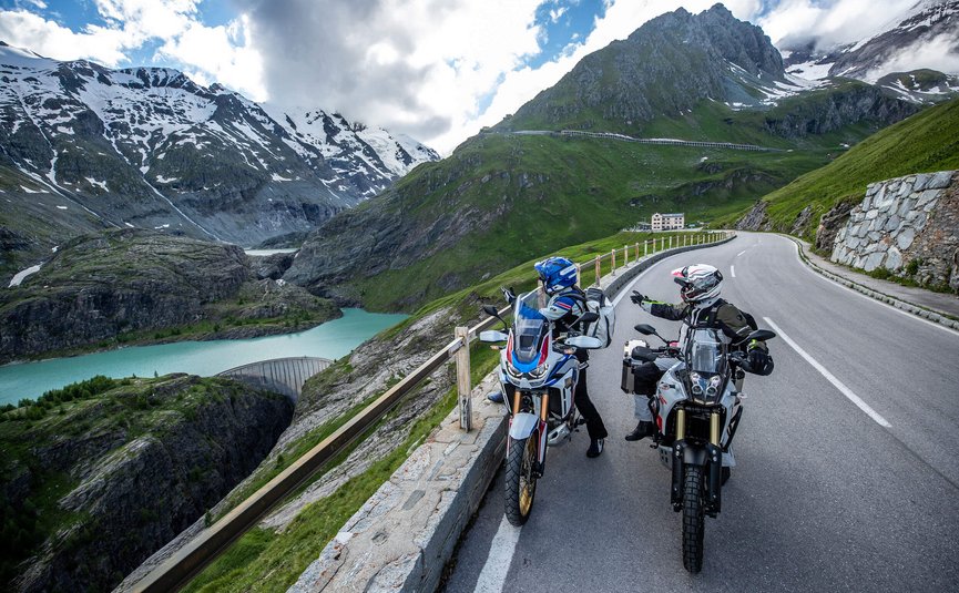 Motorradurlaub: Großglockner – Hohe Tauern © Arturo Rivas Zwei Motorradfahrer auf Alpenstraße mit Bergsee und schneebedeckten Gipfeln