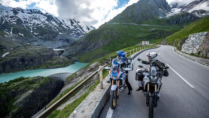 Großglockner – Hohe Tauern © Arturo Rivas Zwei Motorradfahrer auf Alpenstraße mit Bergsee und schneebedeckten Gipfeln