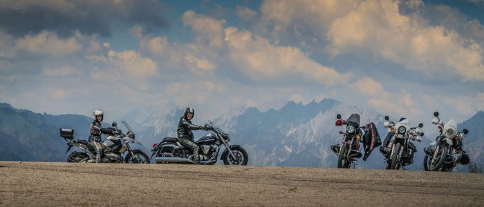 Friaul – Karnien © Moppetfoto.de Motorradfahrer mit ihren Motorrädern vor Bergkulisse unter bewölktem Himmel