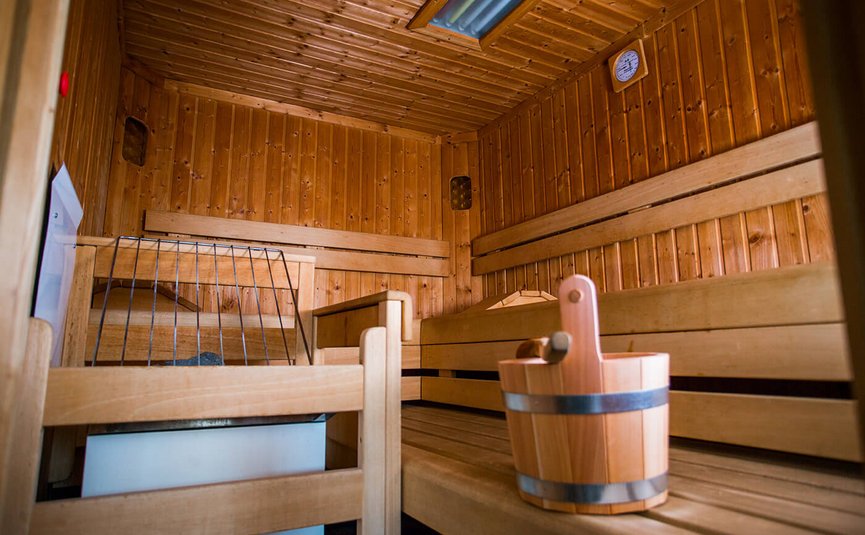 Innenansicht einer Sauna mit Holzbänken und Holzeimer