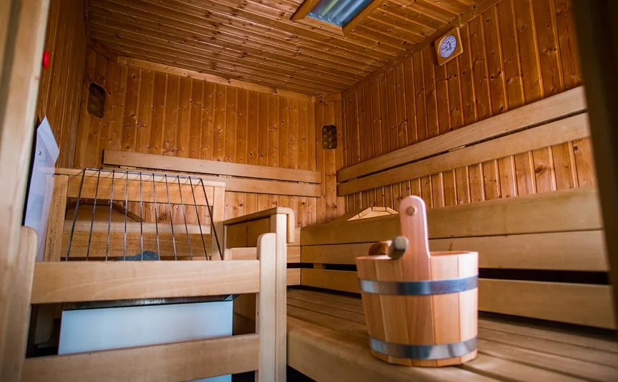 Inside view of a sauna with wooden benches and a wooden bucket