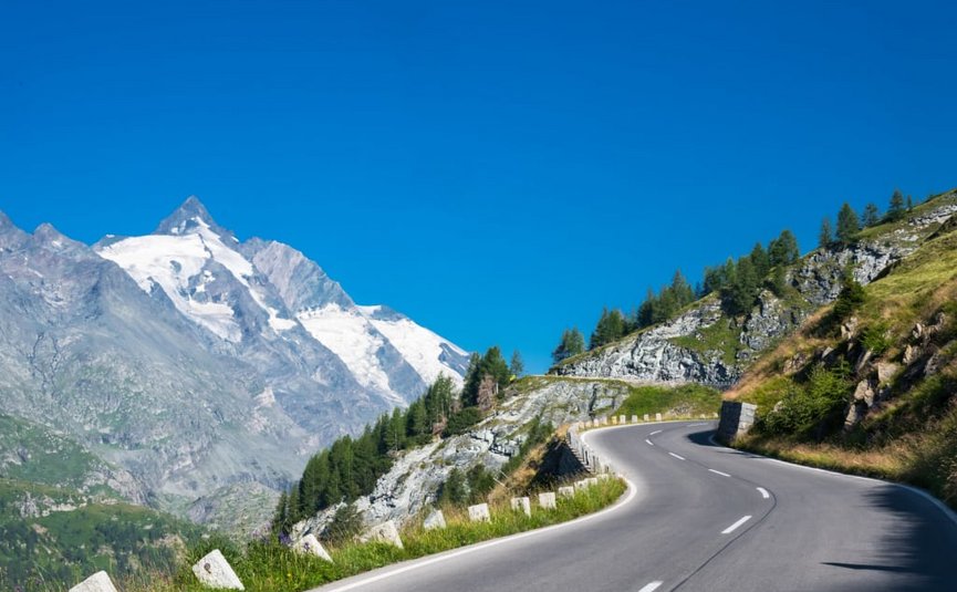 2 Nächte Kurvenkönig Special ab € 244,- pro Person Kronkelende bergweg met besneeuwde toppen en heldere blauwe lucht