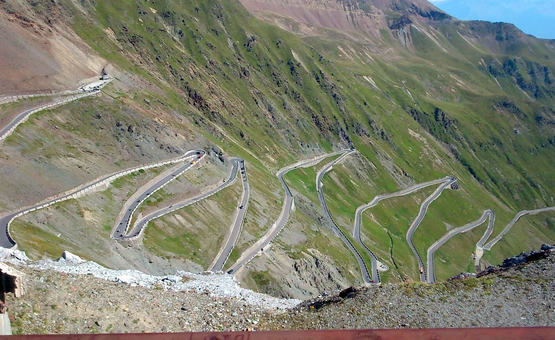 Serpentinenstraße an einem steilen, grünen Berghang