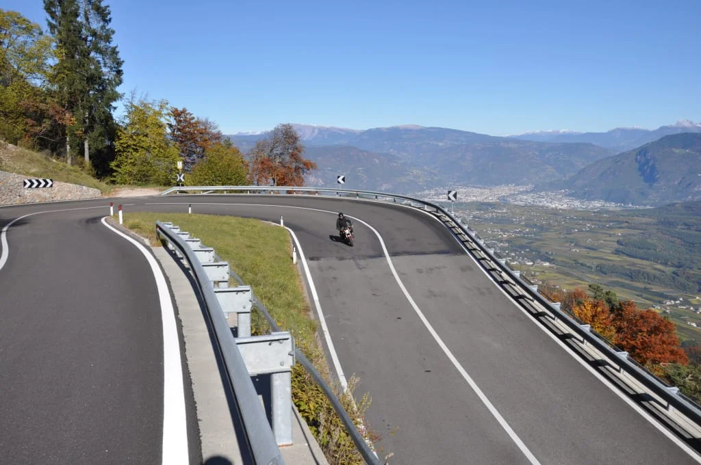 Curvy mountain road with motorcyclist and view of valley and mountains