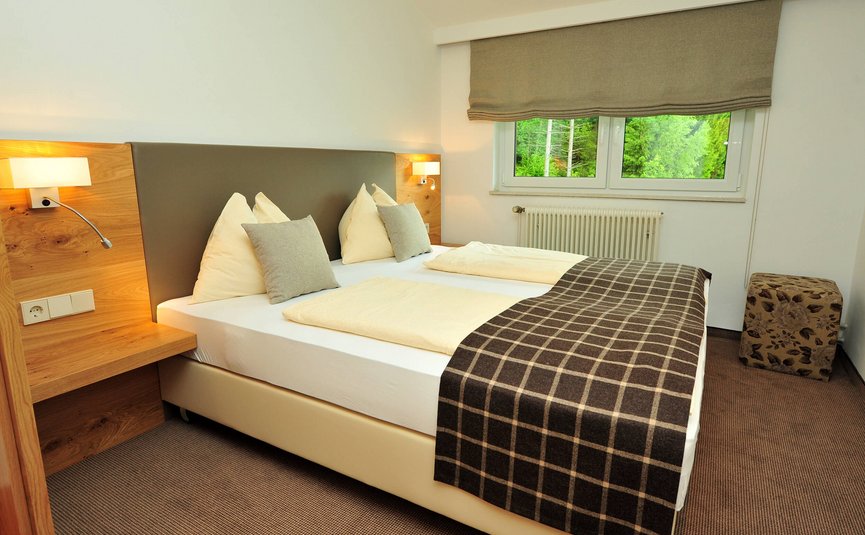 Gemütliches Doppelzimmer mit großen Kissen und braunem Fensterrollo