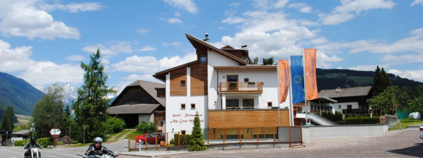 Moar's Bike & Relax Week Motorradfahrer auf Straße vor Hotel in Berglandschaft bei blauem Himmel
