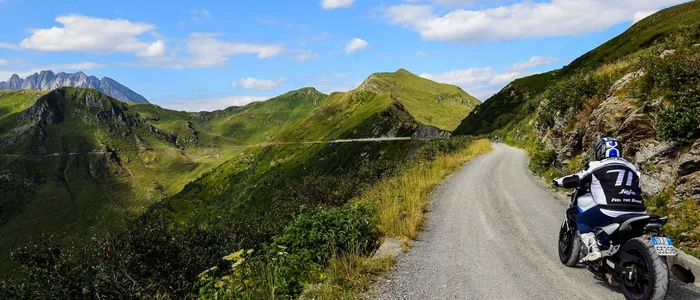 Motorcyclist riding on mountain road with green hills and blue sky