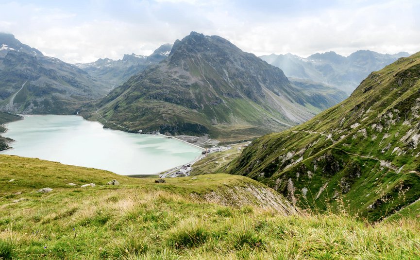 Motorradurlaub im Paznaun – Silvretta © Montafon Tourismus GmbH - Andreas Haller Bergsee und grüne Alpenhänge bei bewölktem Himmel