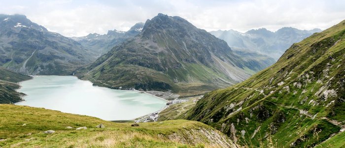 Motorradurlaub in Vorarlberg © Montafon Tourismus GmbH - Andreas Haller Bergsee und grüne Alpenhänge bei bewölktem Himmel