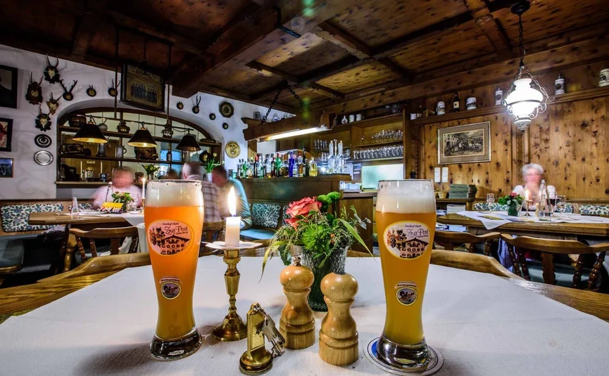 Two beer glasses and candle on table in rustic pub with wooden ceiling