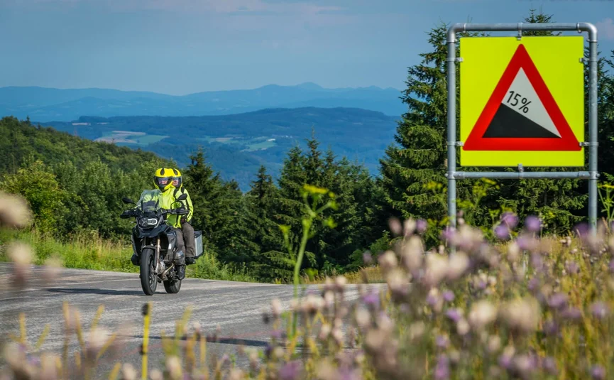 Pre-Alps ...the curvy one Motorcyclist riding on road with 15 percent steep descent sign