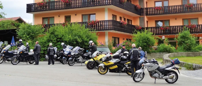 Motorcyclists parked in front of a hotel with balconies and flowers