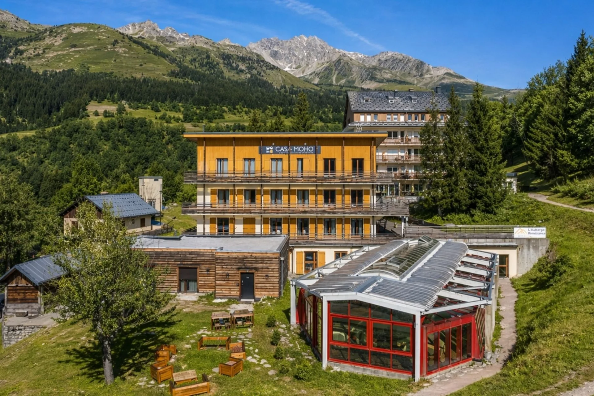 Motorradurlaub © CASA MOHO Saint-François-Longchamp Hotelgebäude in den Bergen mit grünem Wald und blauem Himmel