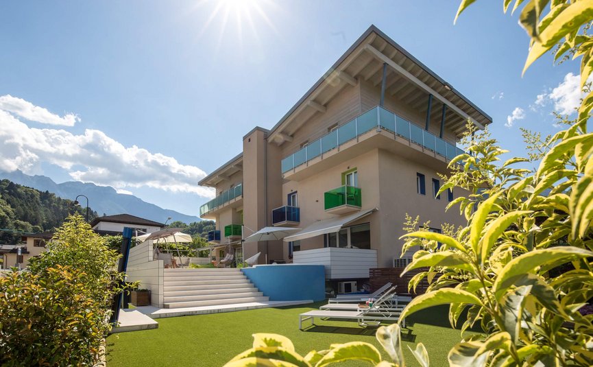 Modernes Gebäude mit Balkon und Garten unter sonnigem Himmel