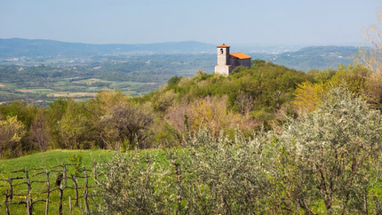 Kerk op een beboste heuvel met vallei en bergen op de achtergrond