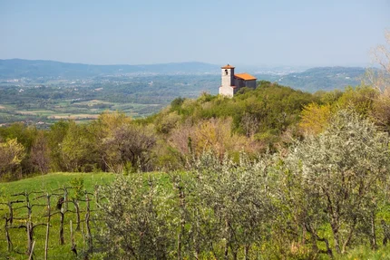 Church on a wooded hill with valley and mountains in the background