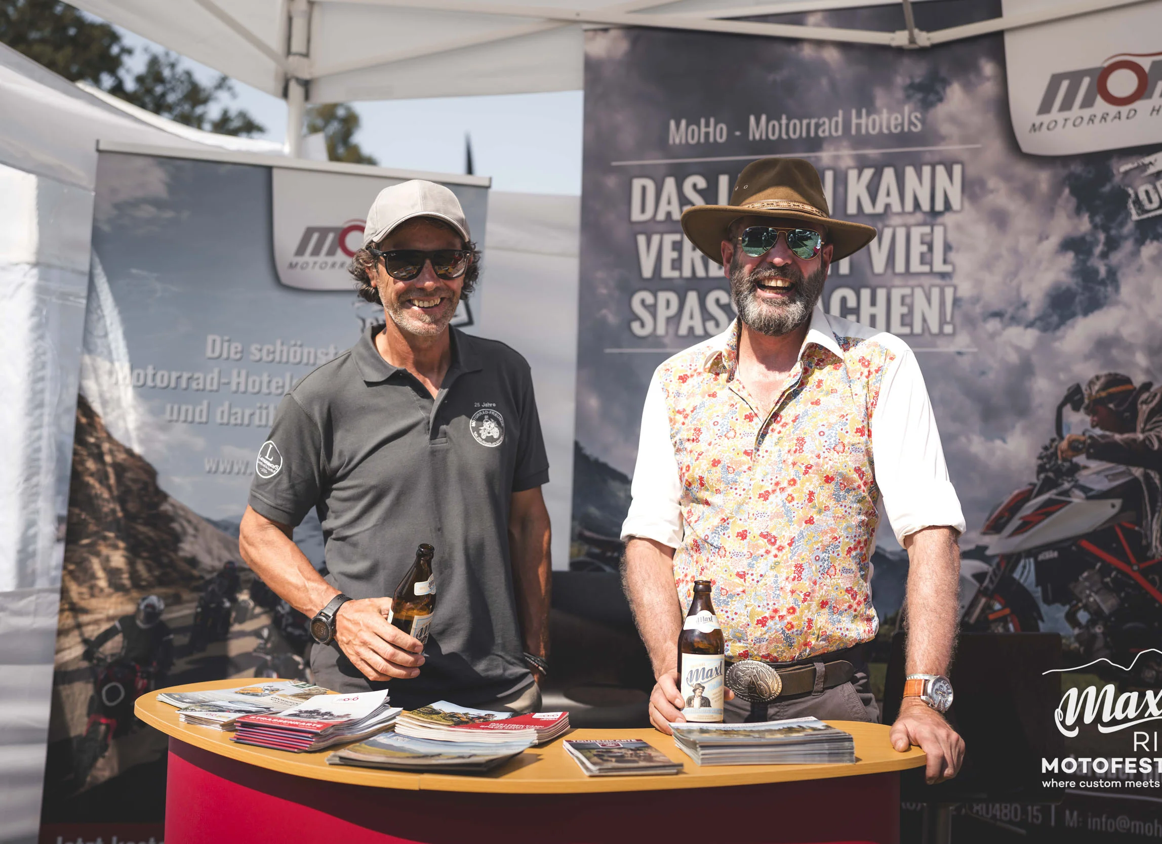 MoHo Messekalender © MaxlRide - Amelie Mesecke Zwei Männer stehen am Infostand mit Bierflaschen auf einem Motorradevent