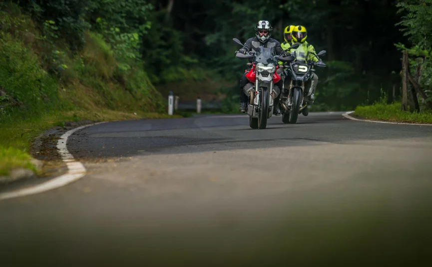 Pre-Alps ...the curvy one Two motorcyclists riding on a winding road through a forest