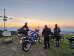 Ferienregion Wolfsberg – Region Lavanttal © Viktor Sator Drei Motorradfahrer schauen bei Sonnenuntergang vom Berggipfel mit Gipfelkreuz