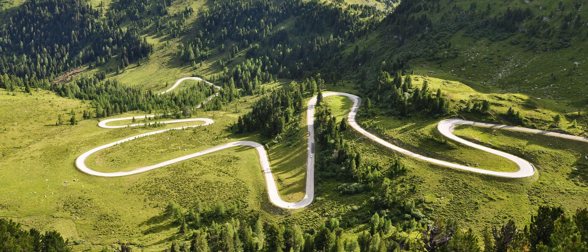 Kurvige Bergstraße durch grüne Landschaft und Hügel