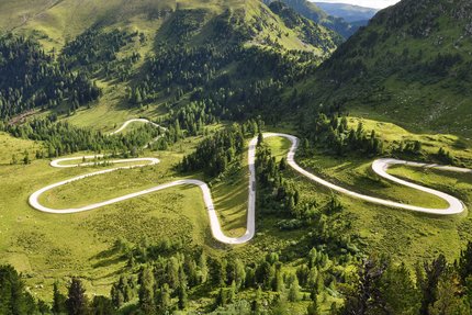 Kurvige Bergstraße durch grüne Landschaft und Hügel