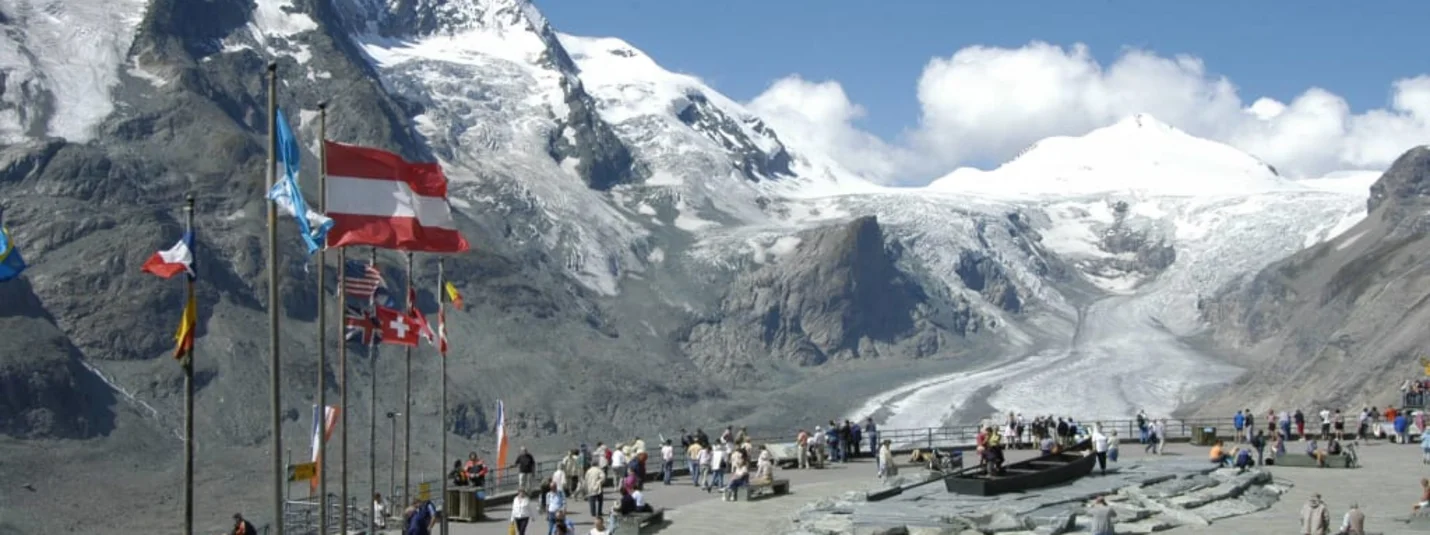 2 Center Tour Großglockner Besucher am Gletscher mit Bergpanorama und Fahnen im Hintergrund