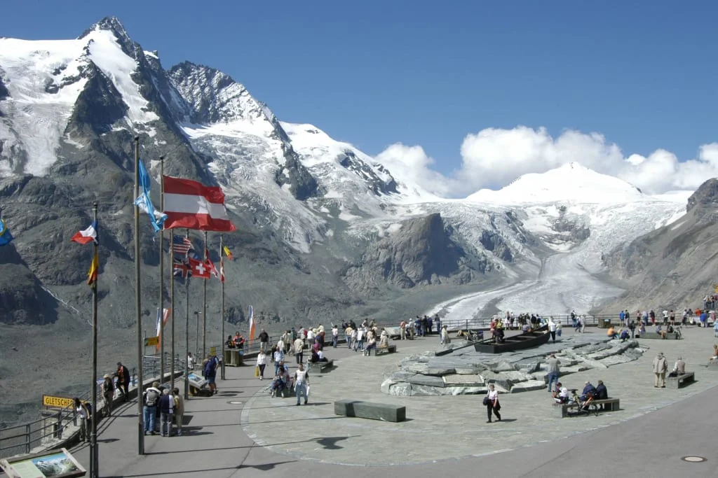 2 Center Tour Großglockner Besucher am Gletscher mit Bergpanorama und Fahnen im Hintergrund