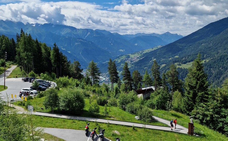 Motorräder auf Bergparkplatz mit Blick auf bewaldete Berge und blauen Himmel