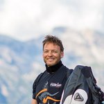 Motorvakanties in Zuid-Tirol en de Dolomieten © Arik Oberrauch Man staat naast rode motor op bergweg met berglandschap op de achtergrond