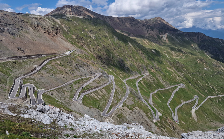 MoHo Schönauer Hof Tour Stelvio Variant 3 Livigno Winding mountain road with sharp curves on green hillside
