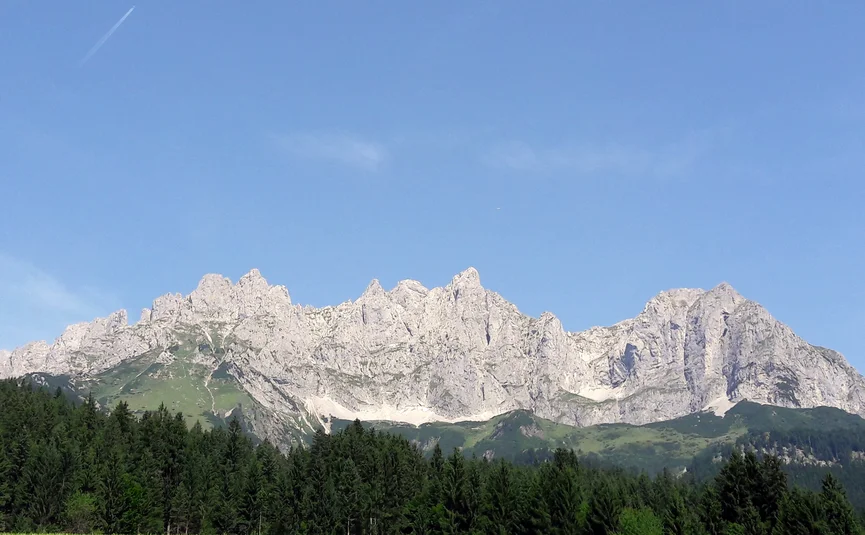 16 Hotel Sonnleiten: Wilder Kaiser circuit ("Koasaumrundung") Rotsachtige bergketen onder een heldere blauwe hemel met bos op de voorgrond