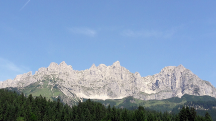 Felsige Bergkette unter klarem blauen Himmel mit Wald im Vordergrund