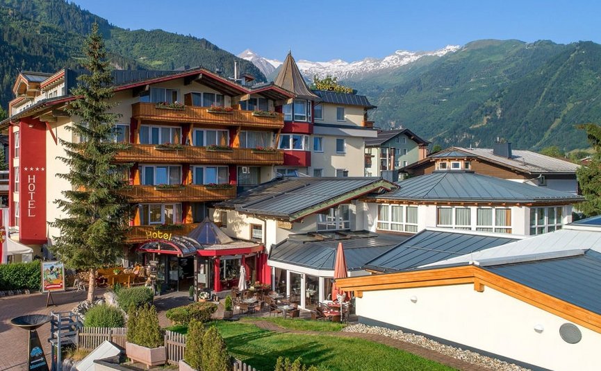 Hotel building with terrace in front of mountains and clear blue sky