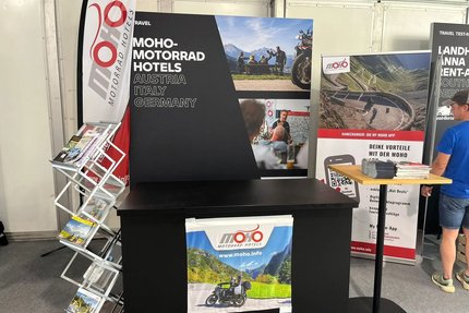 Messestand von MOHO Motorrad Hotels mit Broschüren und Infotafeln