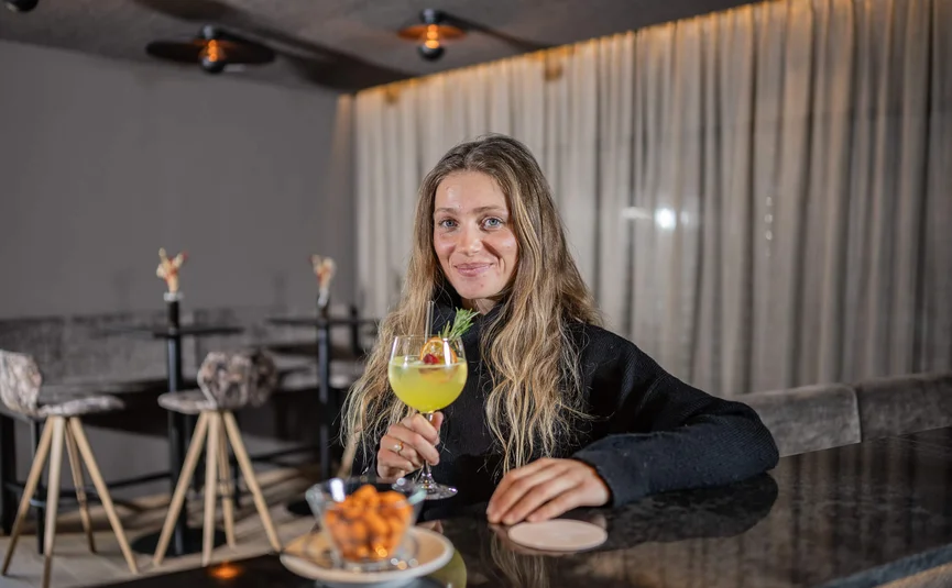 Woman with long hair holding a cocktail glass in a bar