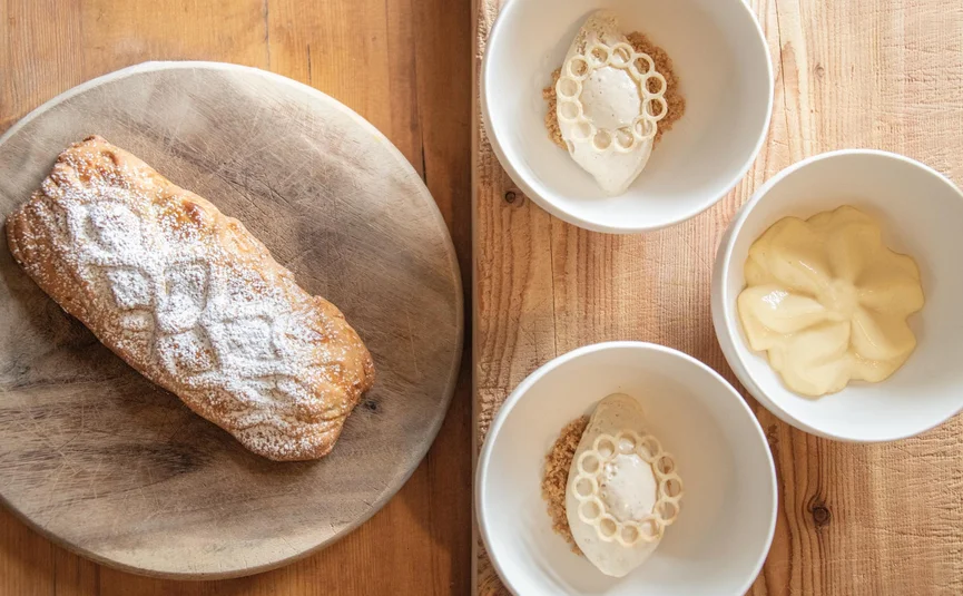 Pastry on wooden board and three bowls with different creams on wooden table