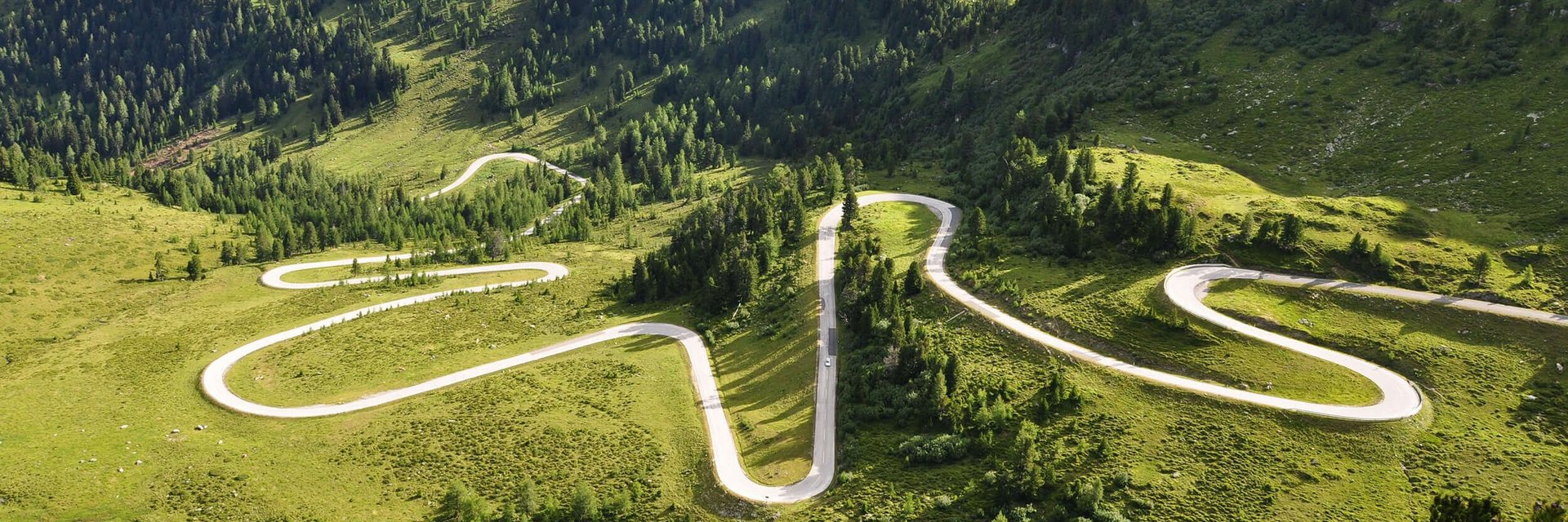 Kurvige Bergstraße durch grüne Landschaft und Hügel