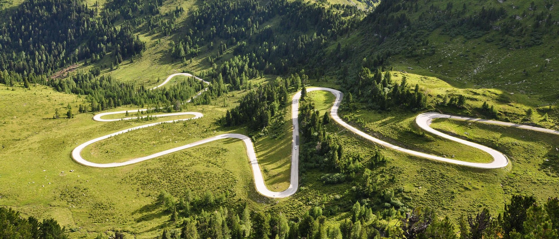 Kronkelende bergweg door groen heuvelachtig landschap