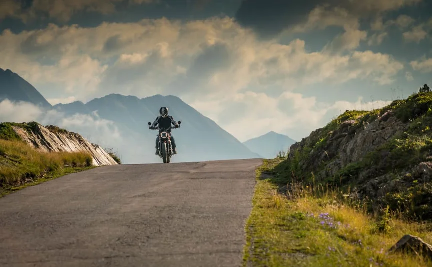 Moar's Bike & Relax Week Motorrijder op een bergweg met bergen en wolken