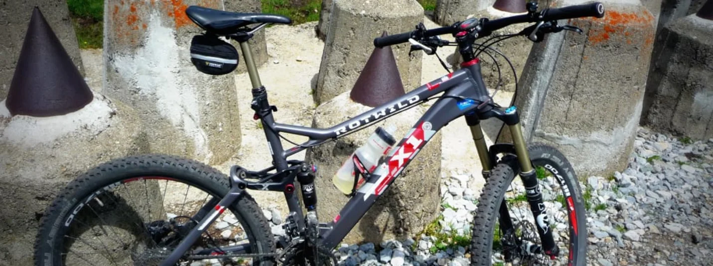 Mountainbike bij betonnen pilaren met metalen punten op grind