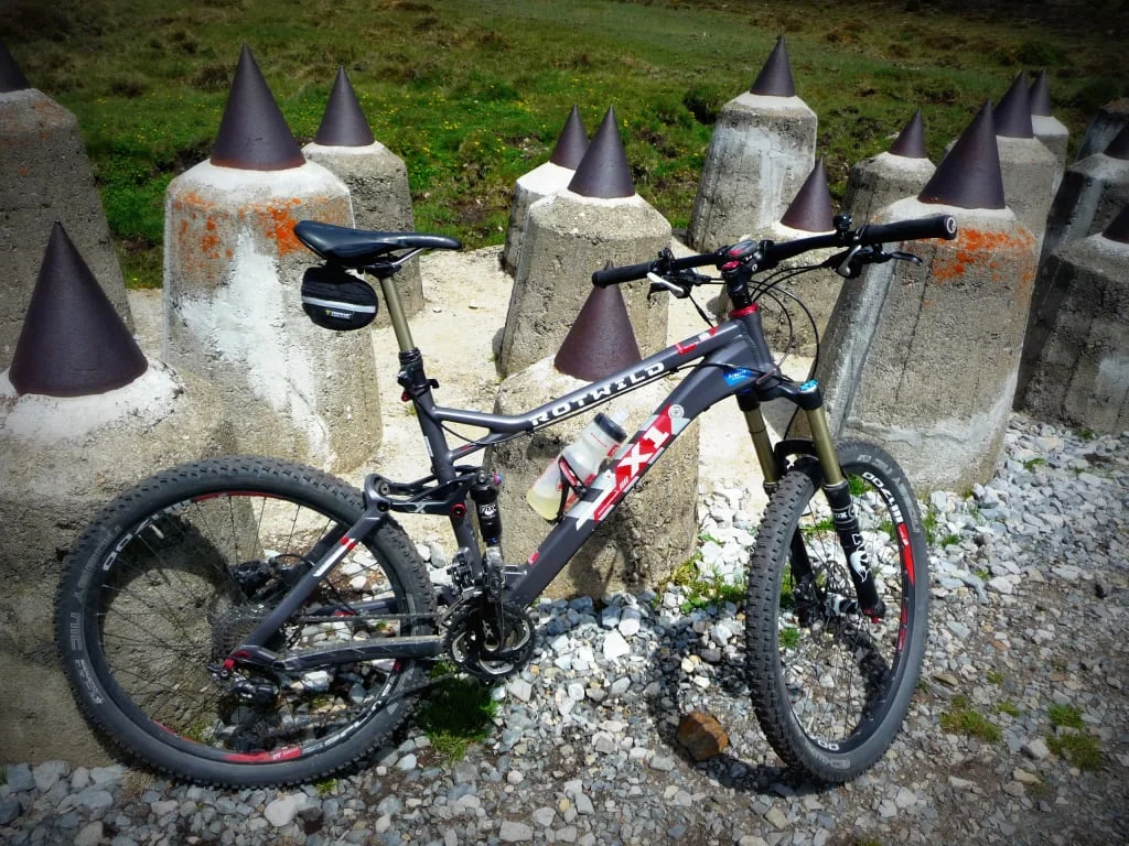 Mountainbike steht vor Betonpfeilern mit metallischen Spitzen auf Schotter