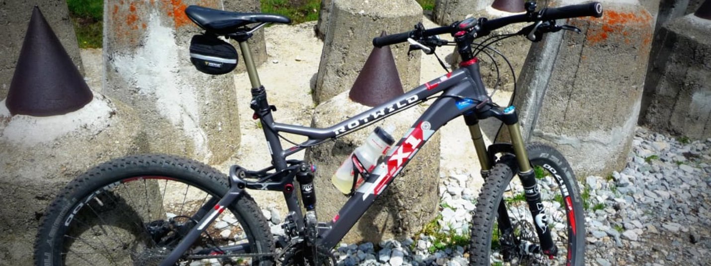 Trail Days Mountainbike steht vor Betonpfeilern mit metallischen Spitzen auf Schotter