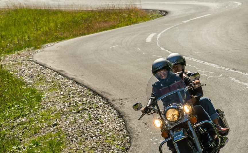 Zwei Personen fahren Motorrad auf kurviger Bergstraße
