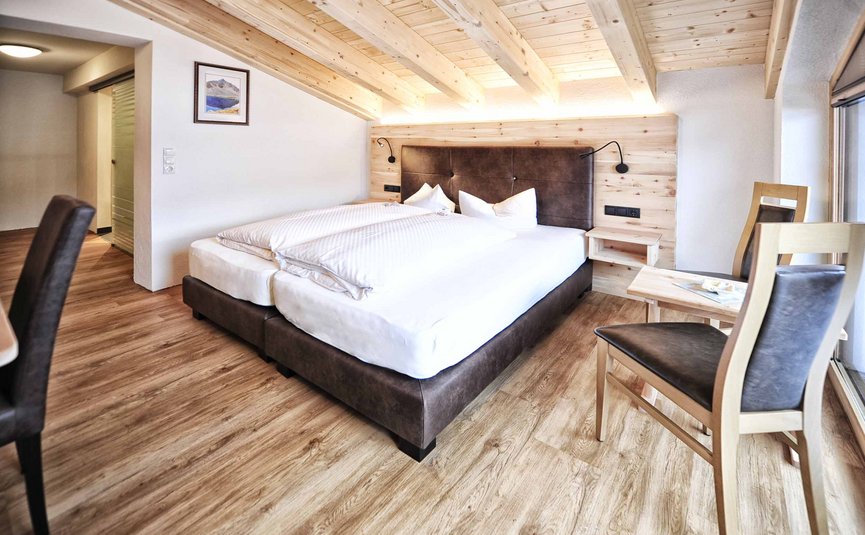 Moderne slaapkamer met houten balkenplafond en bed met bruin hoofdbord