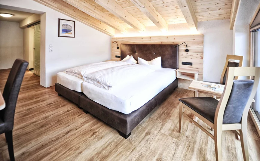 Modernes Schlafzimmer mit Holzbalkendecke und Bett mit braunem Kopfteil