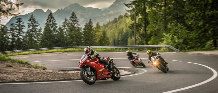 Motorradurlaub in Südtirol und den Dolomiten © Moppetfoto.de Drei Motorräder fahren auf kurviger Bergstraße bei bewölktem Himmel