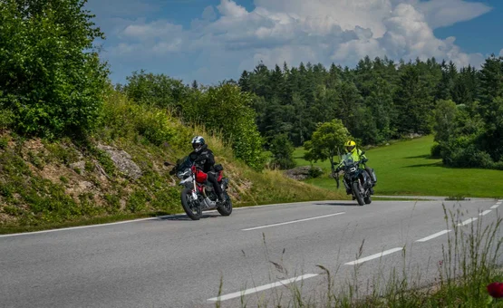 Mühlviertel ..the bear round Two motorcyclists riding on a winding country road with green hills and forest