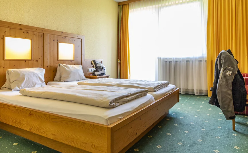 Bright hotel room with two single beds and yellow curtains