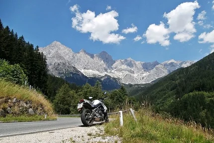 Motorcycle parked on mountain road with Alps and blue sky