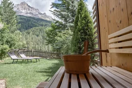 Saunabereich mit Holzeimer, Liegestühlen und Bergblick im Garten